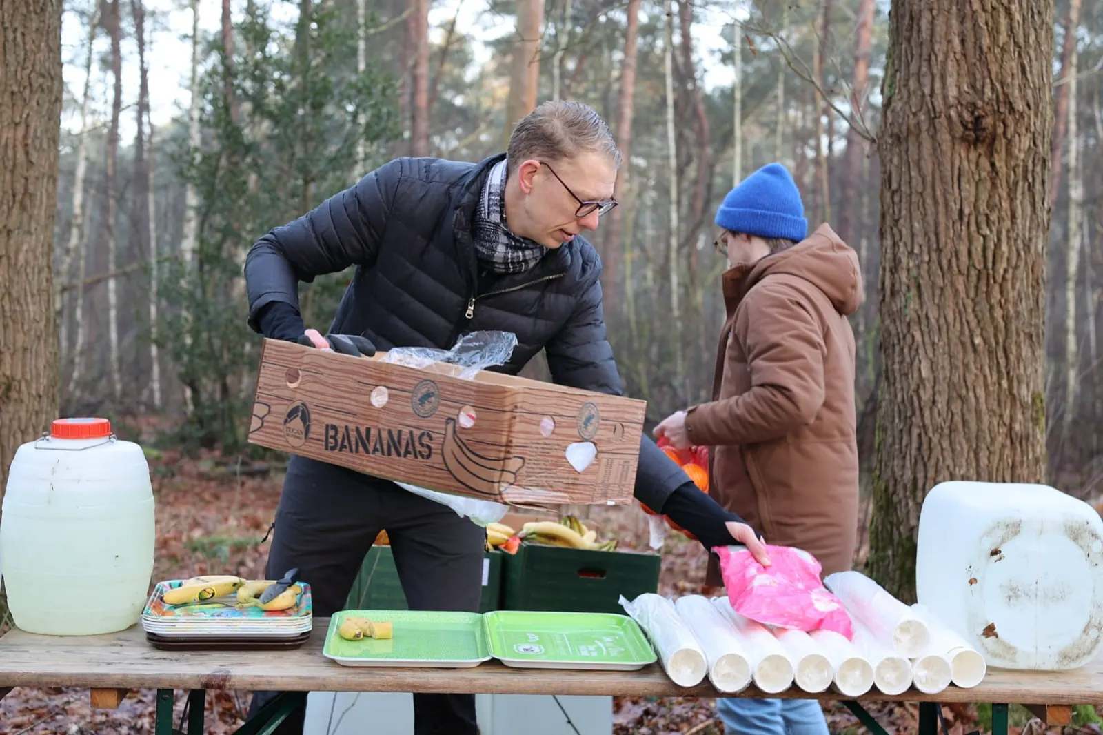 Vrijwilliger pakt bananen en bekers uit bij een bevoorradingspost in het bos