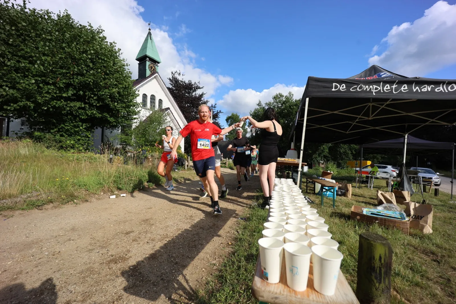 Aanmoediger geeft een high five aan een loper bij de waterpost