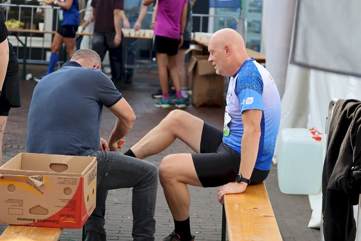 Vrijwilliger reikt een beker aan een loper